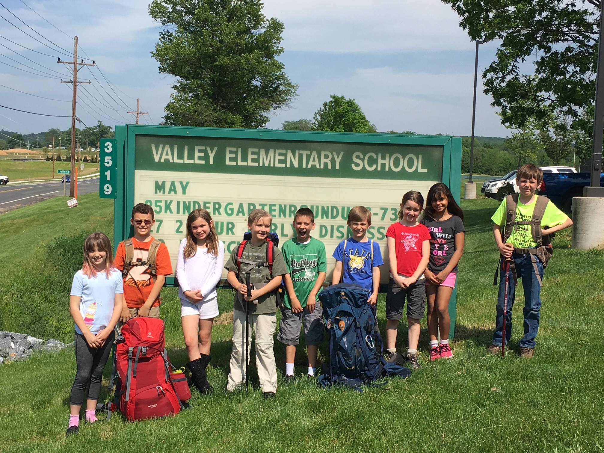 youth educational adventures members posing together by the valley elementary school sign