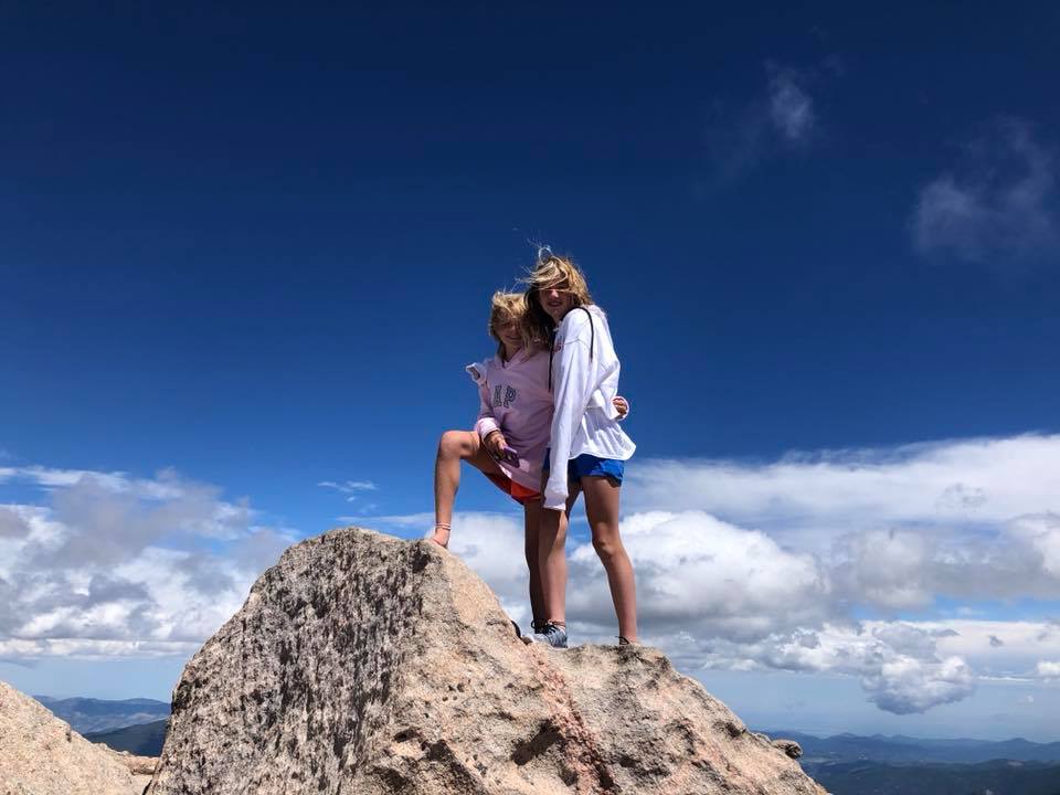 two youth educational adventures members posing together on a high rock