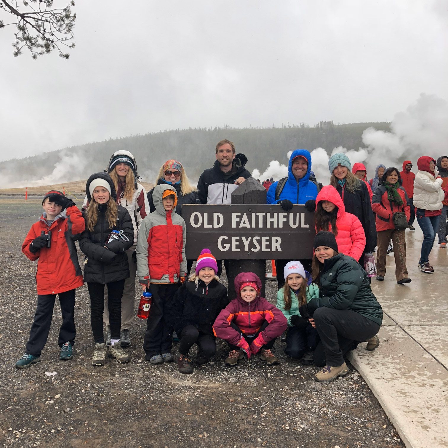 youth educational adventures group posing together by the old faithful geyser sign