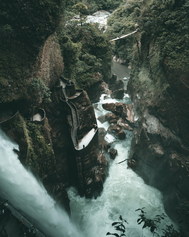 tourists exploring steep ruins in ecuador that are surrounded by waterfalls