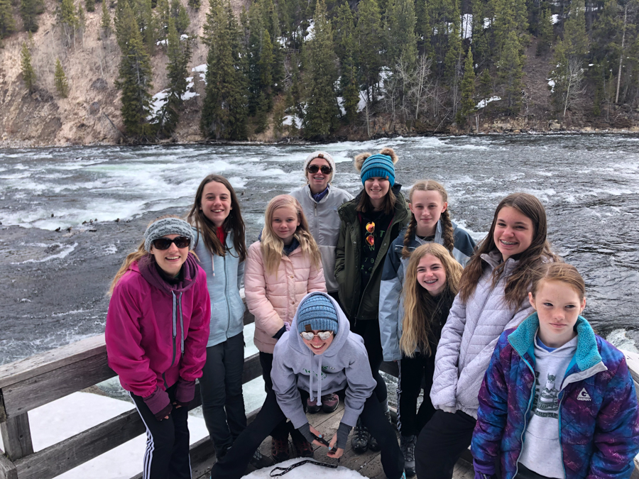 youth educational adventures group smiling by rushing waters in yellowstone national park