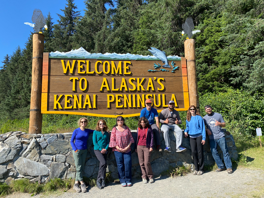 adventures for all members posing by the welcome to alaska's kenai peninsula sign