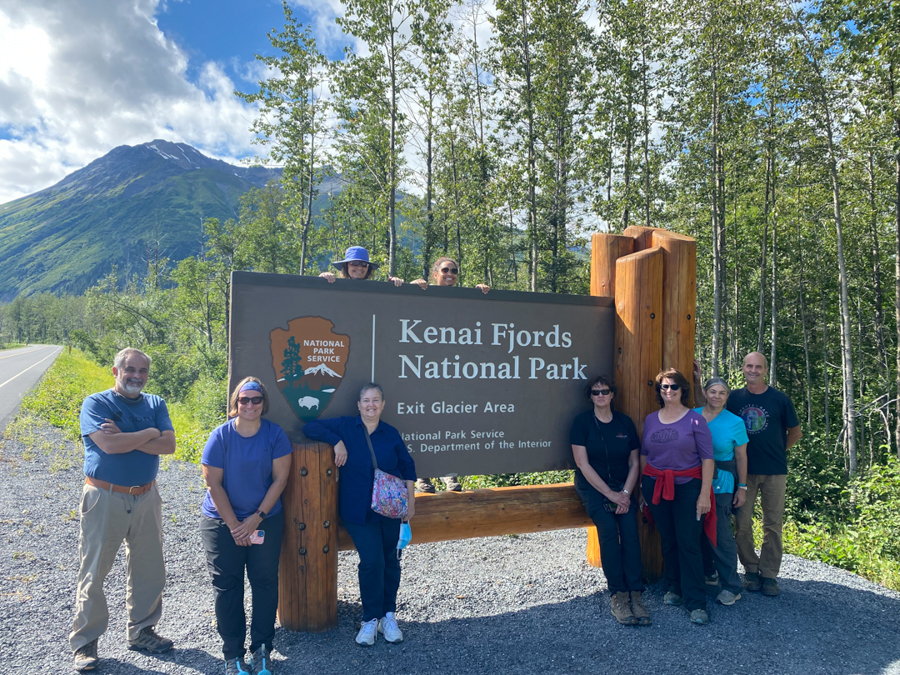 adventures for all group posing next to the kenai fjords national park sign in alaska