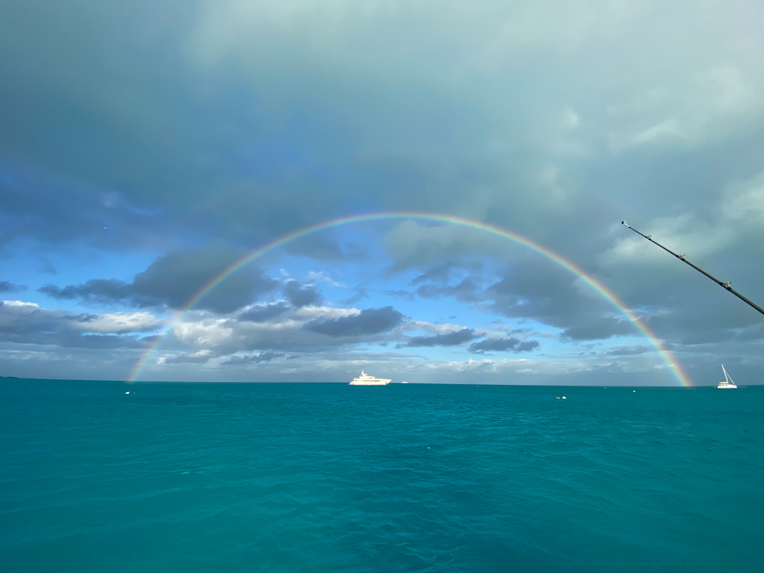 rainbow arching over a boat on turquoise waters