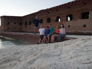 adventures for all group members sitting by a brick wall on the beach in the dry tortugas