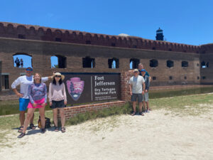 adventures for all group members posing by the fort jefferson dry tortugas national park sign