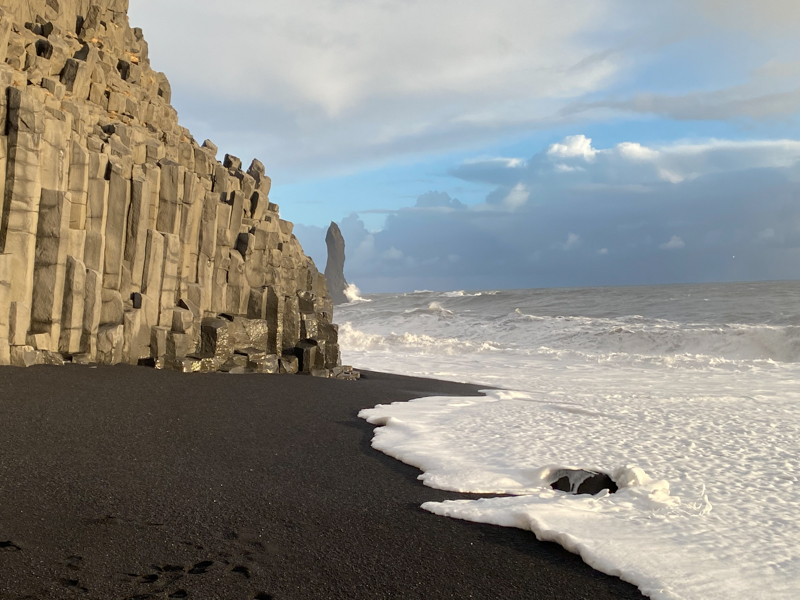 black sand beaches of iceland with grey ocean waters coming onto the beach