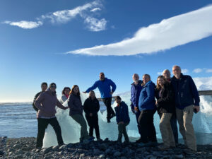 adventures for all group posing with a large chunk of ice on a beach in iceland