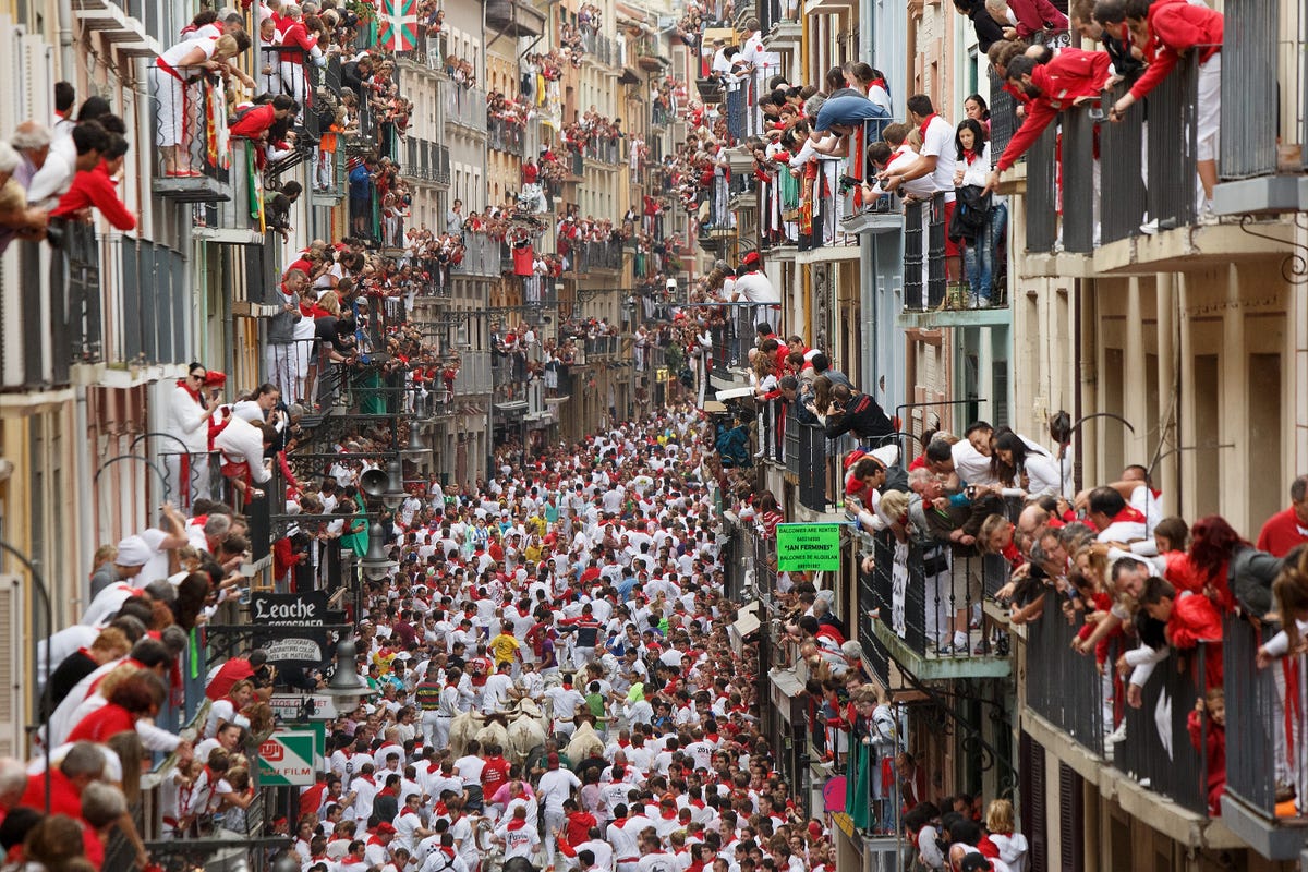 swarms of people in white and red celebrating the running of the bulls festival