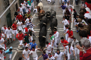 group of men running from bulls in the streets of spain