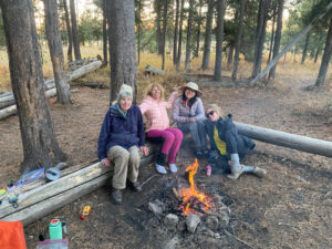 adventures for all members resting on log benches by a campfire