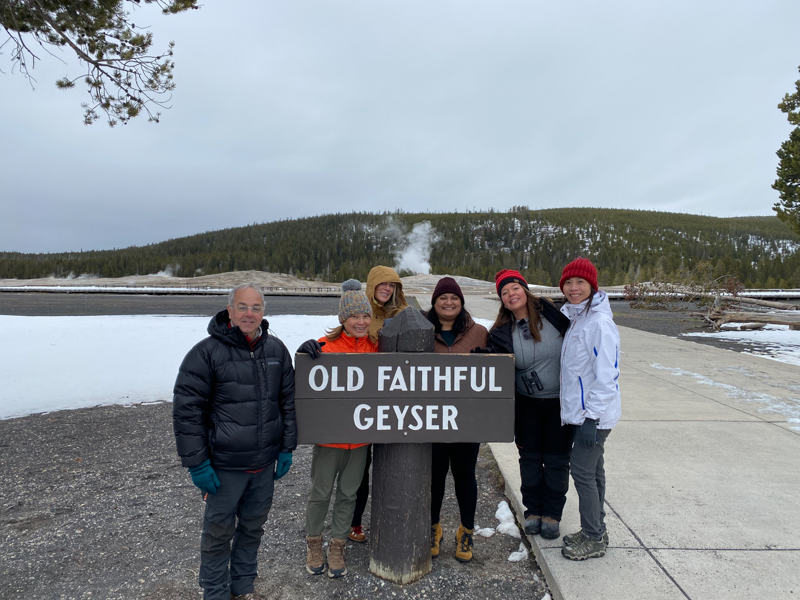adventures for all group standing with old faithful geyser sign with old faithful in the background