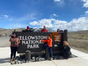 adventures for all group members posing next to the yellowstone national park sign