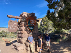 adventures for all group members posing by the zion national park pillar and sign