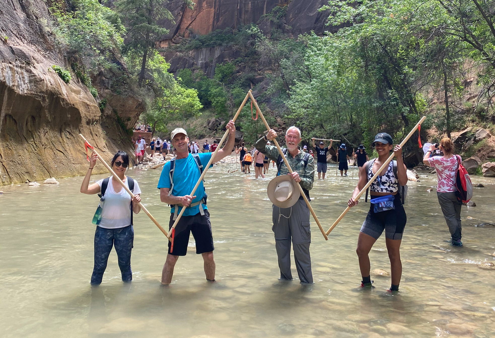group of chaperones holding wooden poles and posing in a river