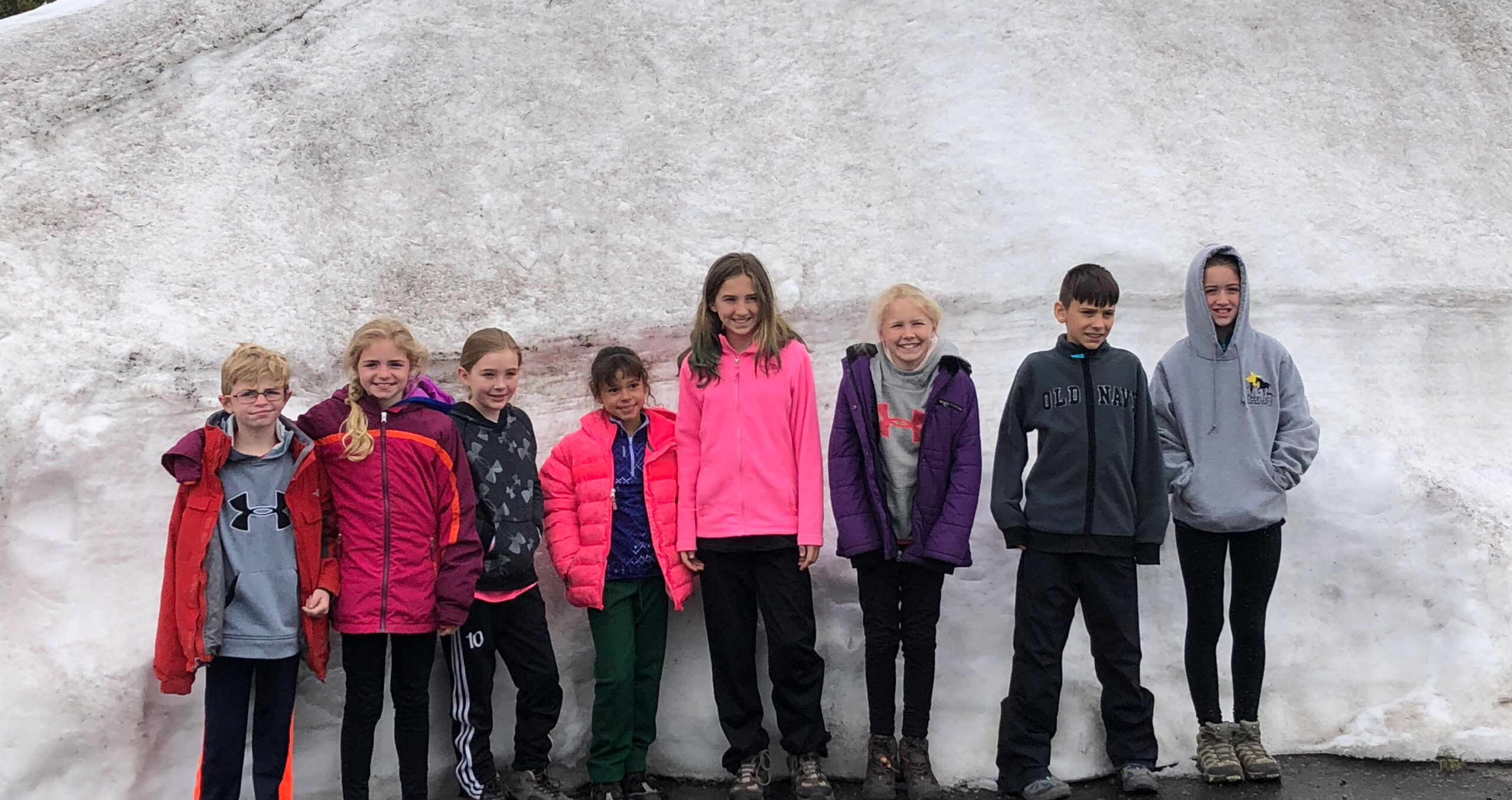 youth educational adventures group posing in front of a wall of snow