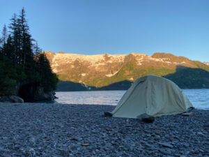 grey tent pitched on rocky shores in alaska