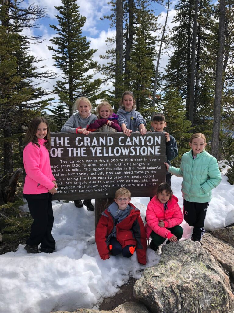 youth educational adventures group standing in a snowbank with the grand canyon of the yellowstone sign