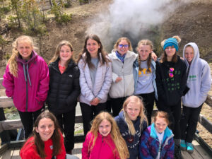 youth educational adventures group smiling and gathered by a small hot spring
