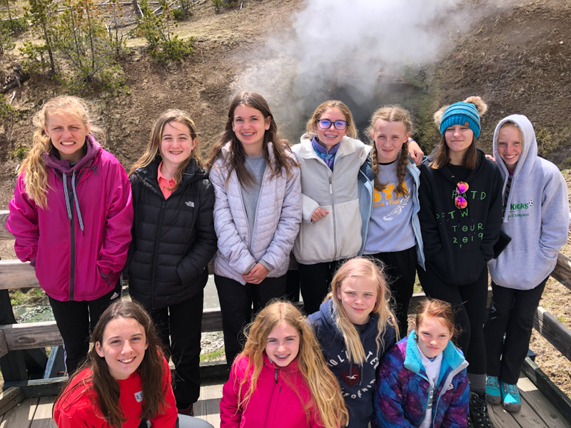 youth educational adventures group smiling and gathered by a small hot spring