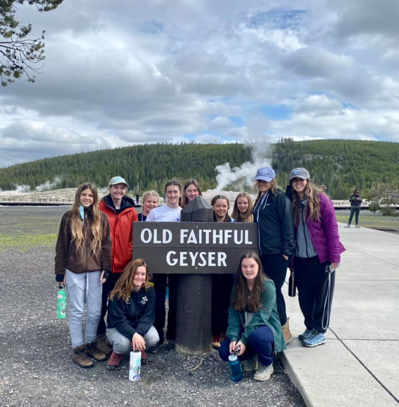 youth educational adventures group smiling next to the old faithful geyser sign