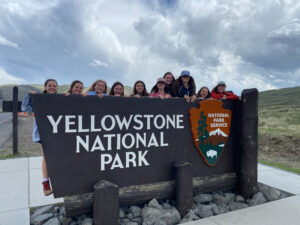 youth educational adventures group posing with yellowstone national park sign