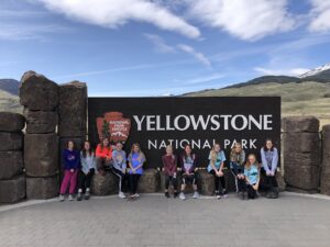 youth educational adventures group in front of the yellowstone national park sign