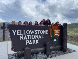 youth educational adventures group posing with the yellowstone national park sign